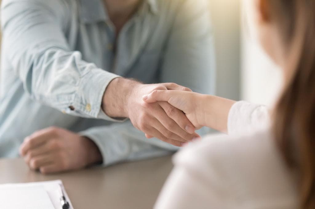 A couple shakes hands during a collaborative divorce attorney meeting.